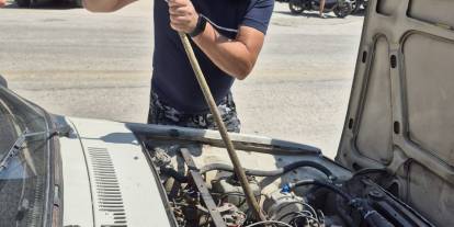 Otomobilin motoruna giren yılanı sopayla çıkardı